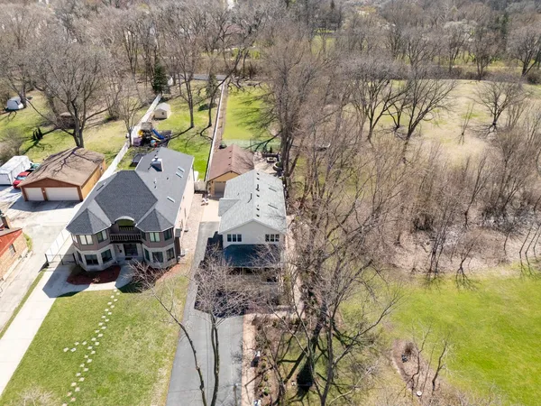 an aerial view of a house with swimming pool and large trees