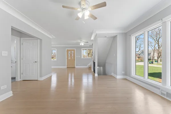 a view of a big room with wooden floor a chandelier fan and windows