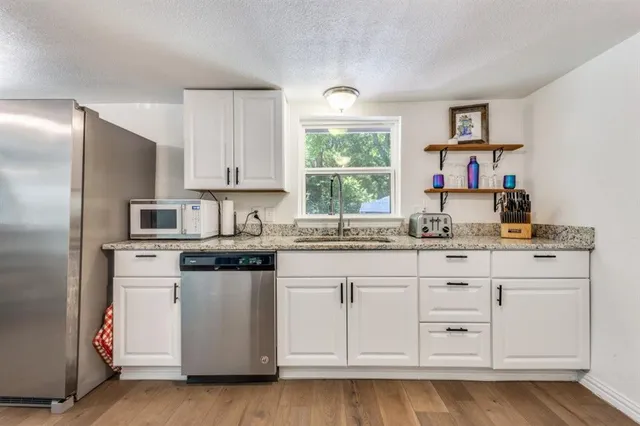 a kitchen with granite countertop white cabinets and white appliances