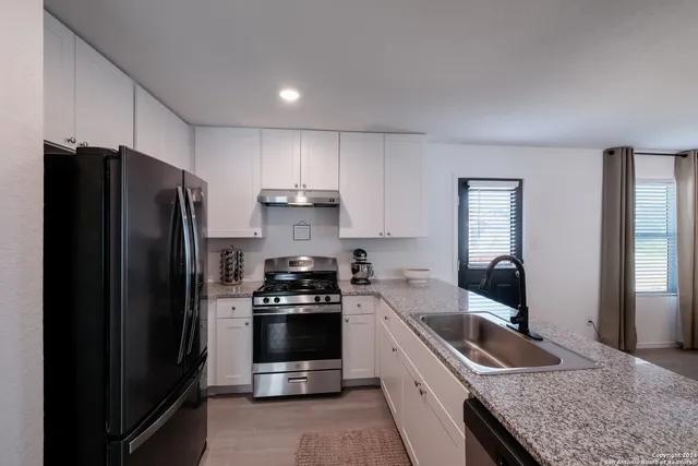a kitchen with granite countertop a refrigerator stove and sink