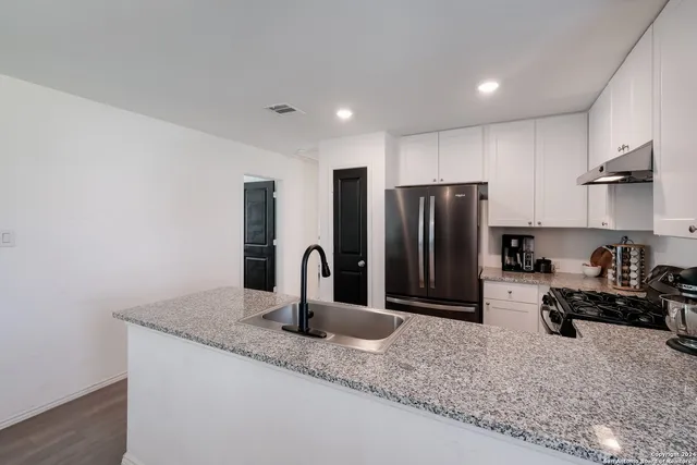 a kitchen with granite countertop a refrigerator and a sink