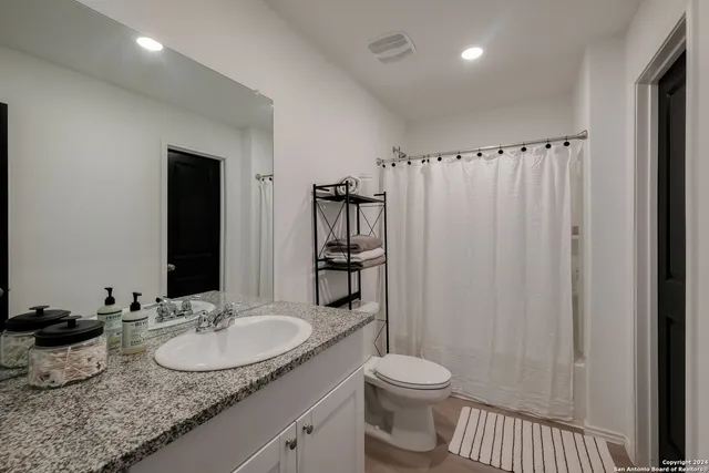 a bathroom with a granite countertop sink and a mirror