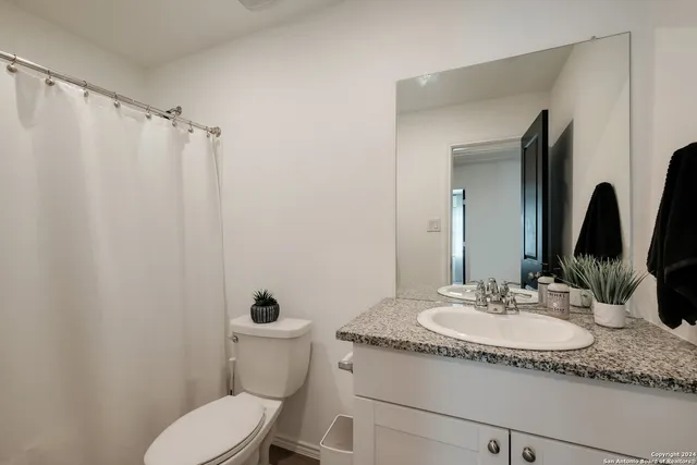 a bathroom with a granite countertop sink toilet and a mirror