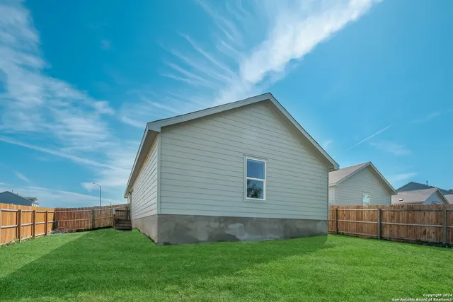 a view of a house with a yard and a large tree