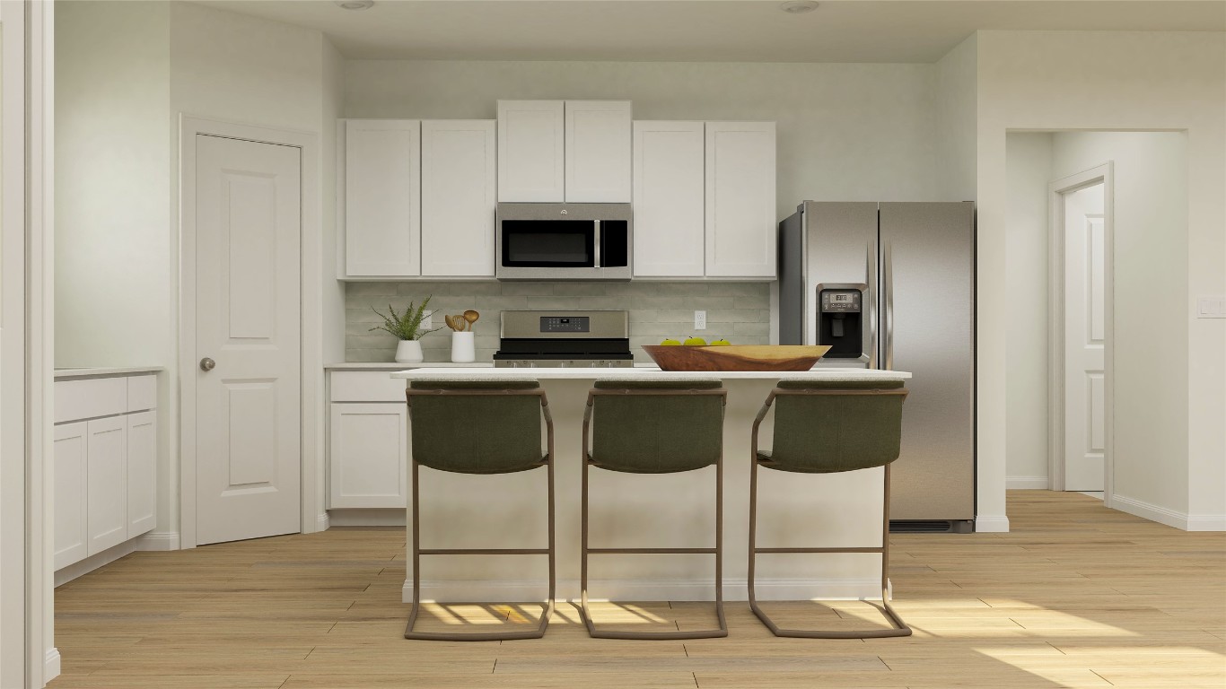 18024 Prairie Falcon Way Pflugerville, TX 78660 - Photo 18 of 23 a kitchen with stainless steel appliances kitchen island granite countertop a sink cabinets and wooden floor