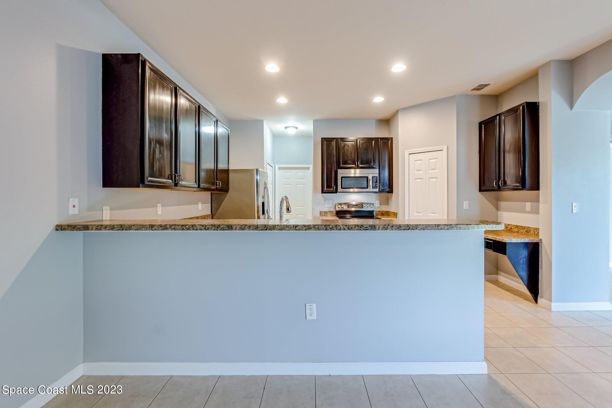 3194 Arden Circle Melbourne, FL 32934 - Photo 25 of 40 a view of kitchen with stainless steel appliances granite countertop refrigerator sink and microwave