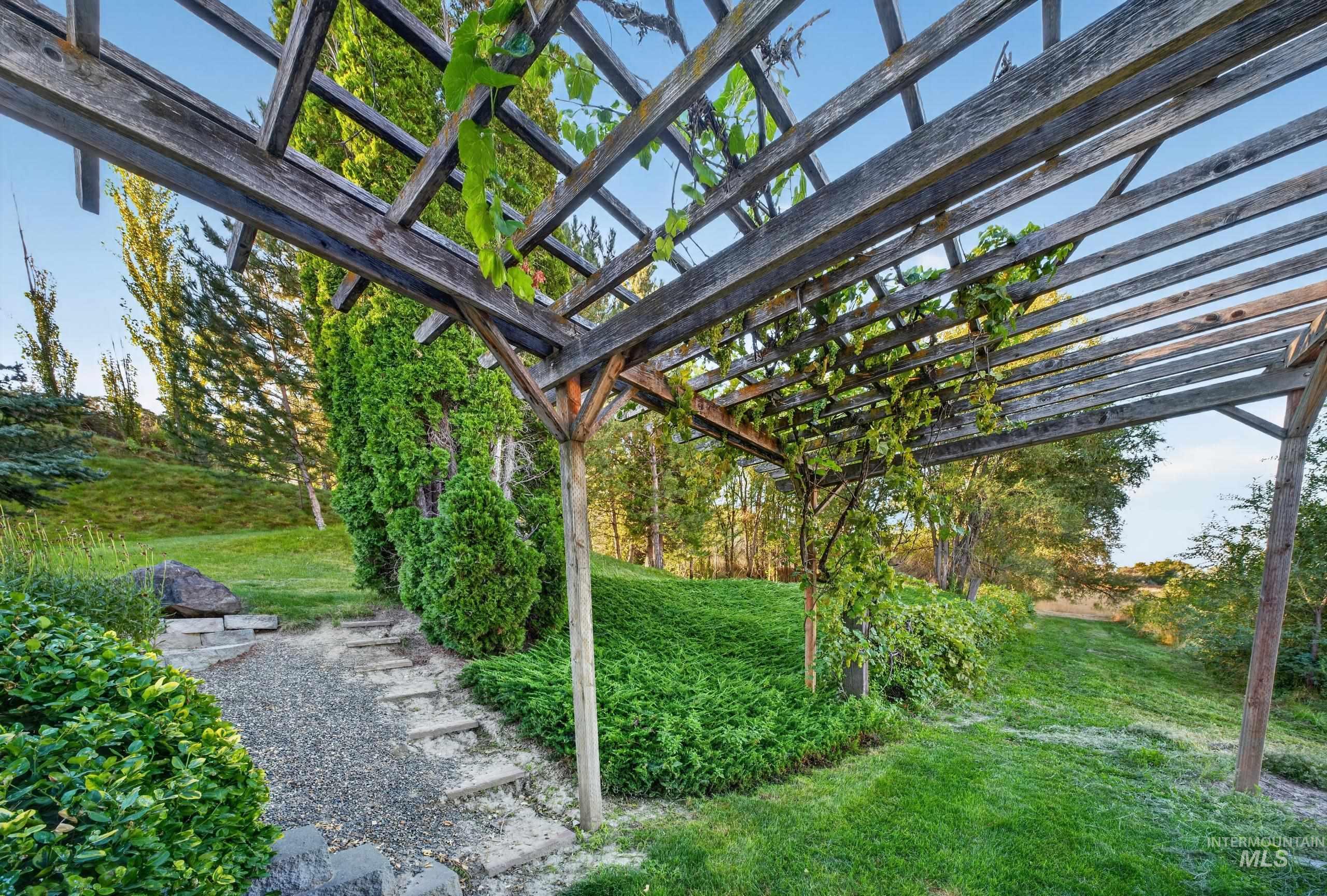 5540 Finley Road Fruitland, ID 83619 - Photo 27 of 50 Wooden pergola structure, gravel path with stone steps, manicured lawn, and established landscaping