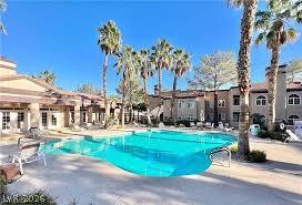 9325 West Desert Inn Road, Unit 278 Las Vegas, NV 89117 - Photo 12 of 17 An inviting pool area, framed by palm trees, offers a refreshing oasis amidst a residential complex.
