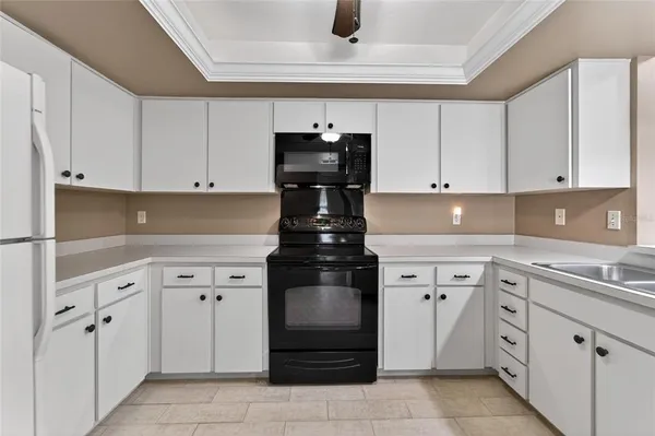 a kitchen with white cabinets and black appliances