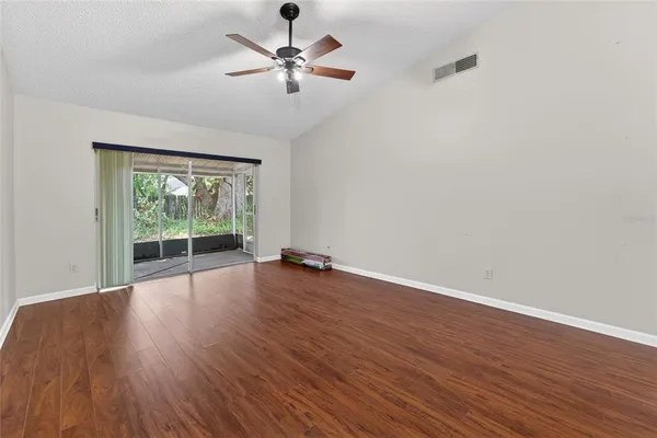 an empty room with wooden floor and chandelier fan