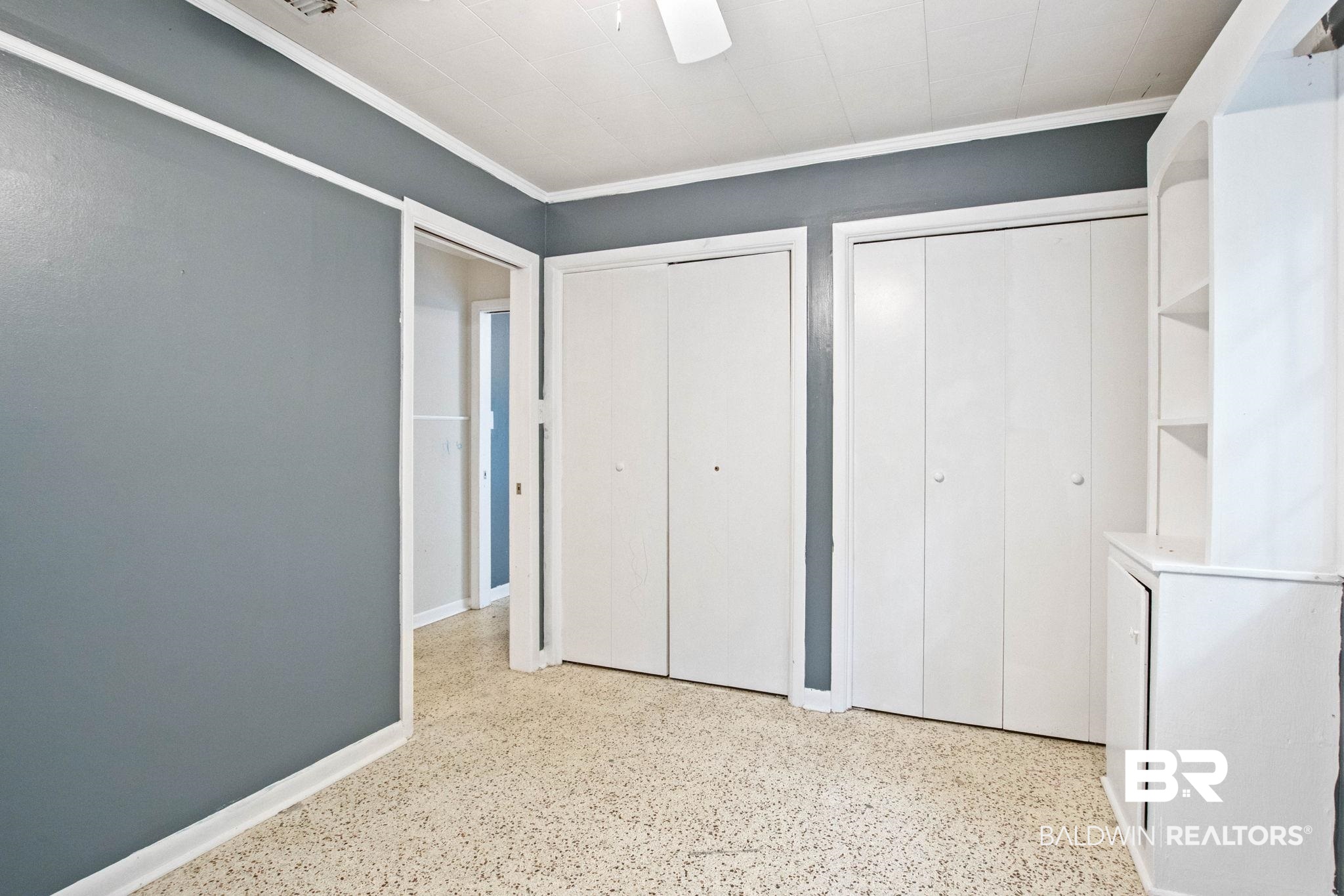 384 Old Bratt Road Atmore, AL 36502 - Photo 44 of 64 Room featuring light-colored speckled flooring, two sets of bi-fold closet doors, and an integrated white shelving unit with lower cabinetry