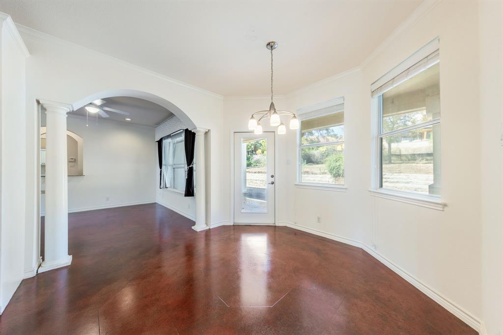 1704 Randolph Ridge Trail Austin, TX 78746 - Photo 11 of 23 Unfurnished breakfast area featuring concrete flooring, crown molding, and ceiling fan with chandelier