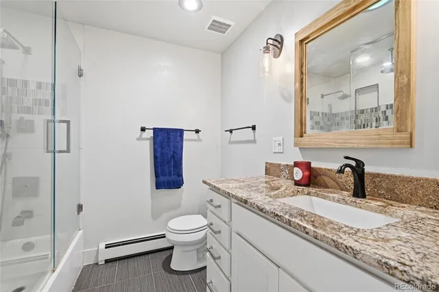 a bathroom with a granite countertop sink toilet and shower