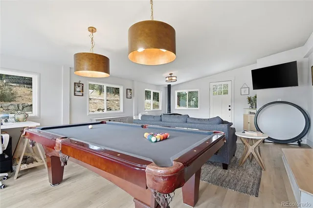 a living room with game table and a flat screen tv