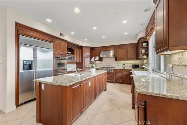 a large kitchen with stainless steel appliances granite countertop a large counter top a stove a sink and a refrigerator