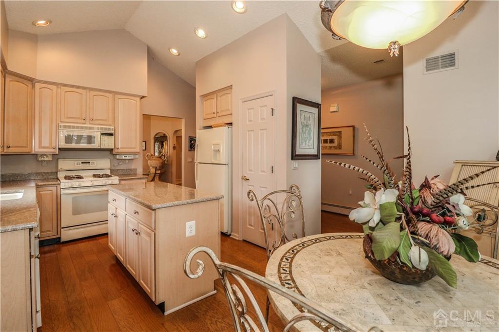 33 Whitehall Road Monroe Township, NJ 08831 - Photo 13 of 25 a kitchen with stainless steel appliances kitchen island granite countertop a sink a stove a refrigerator and white cabinets with wooden floor