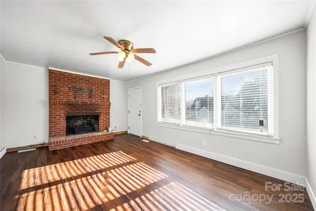 a view of an empty room with chandelier and a fireplace