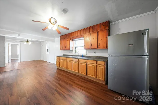 a kitchen with stainless steel appliances granite countertop a refrigerator a sink dishwasher a stove and a refrigerator with wooden floor