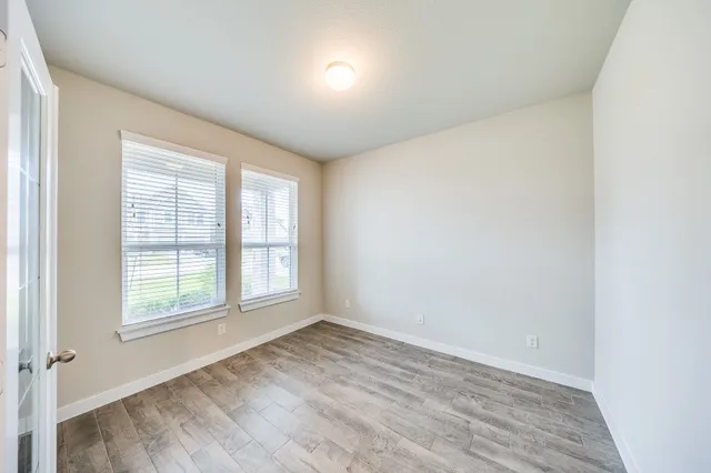 an empty room with wooden floor and windows