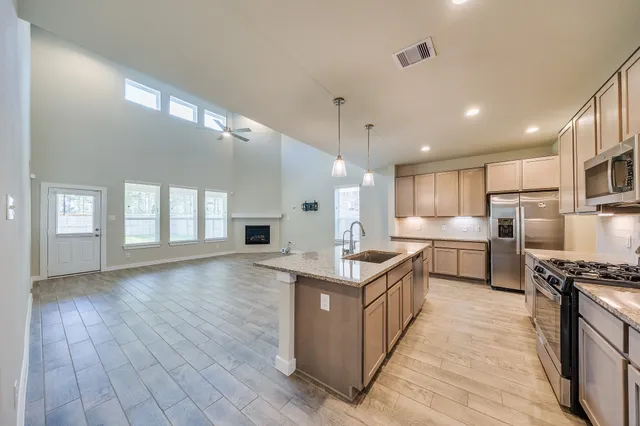 a kitchen with stainless steel appliances kitchen island granite countertop a stove a sink and a refrigerator