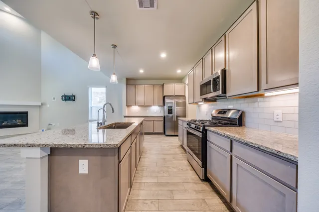 a kitchen with stainless steel appliances granite countertop a sink a stove top oven a counter space and cabinets