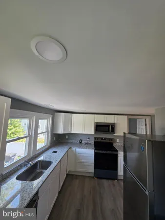 a kitchen with granite countertop a refrigerator stove and sink