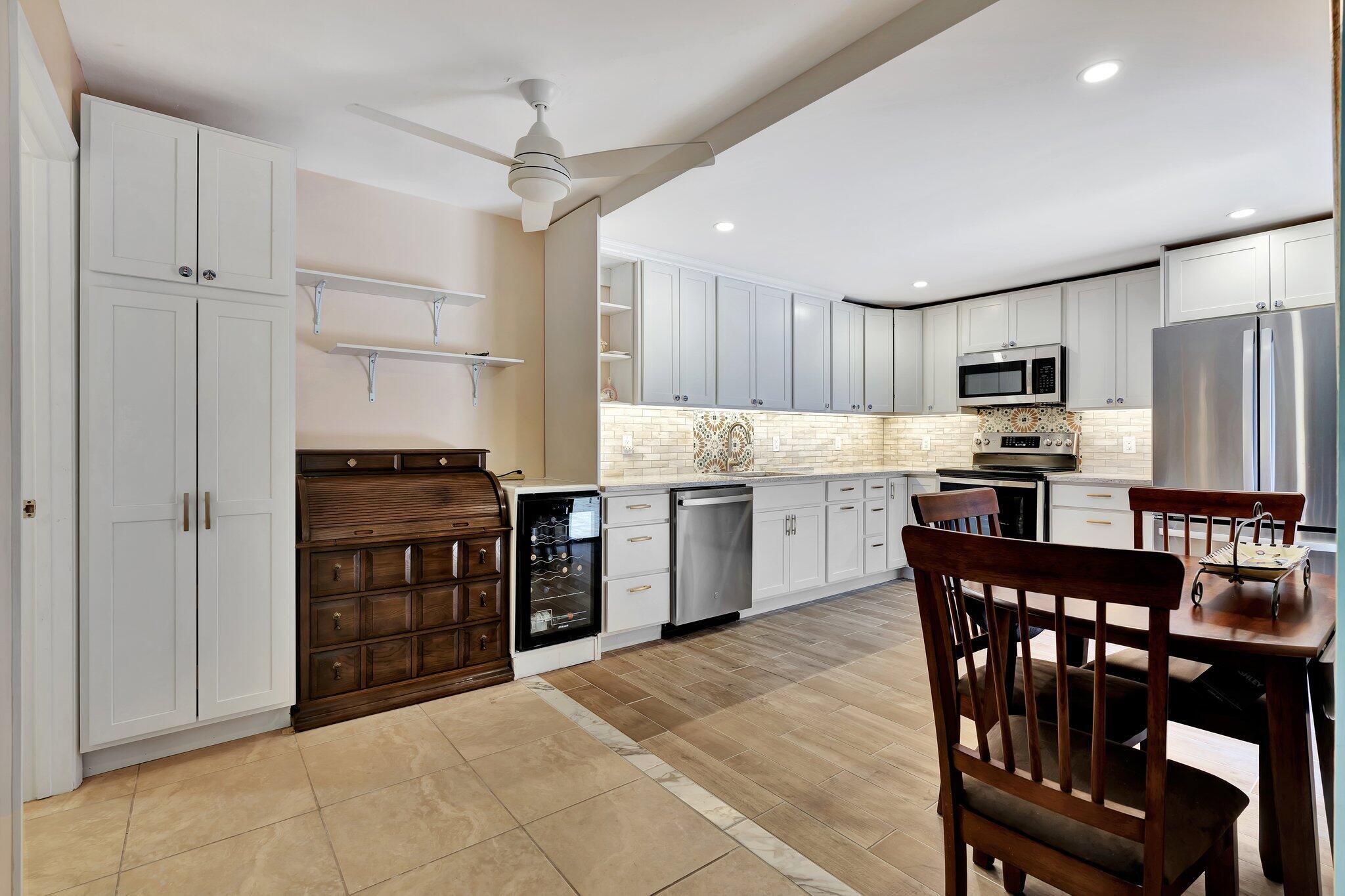 3016 30th Court Jupiter, FL 33477 - Photo 2 of 8 a kitchen with stainless steel appliances a stove a sink dishwasher a refrigerator with a dining table and chairs