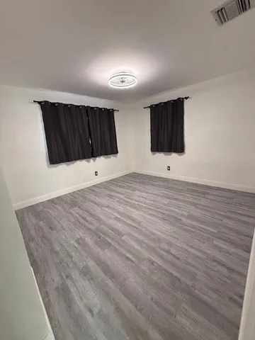 a view of an empty room with wooden floor and windows