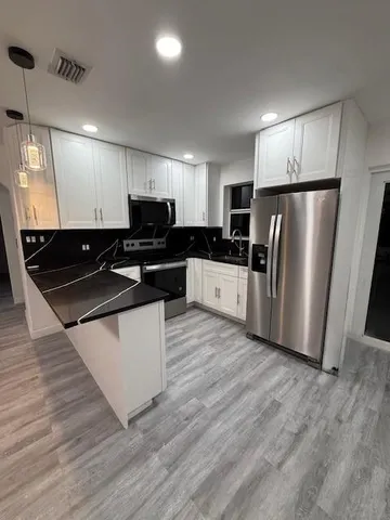a kitchen with stainless steel appliances wooden floor and a refrigerator