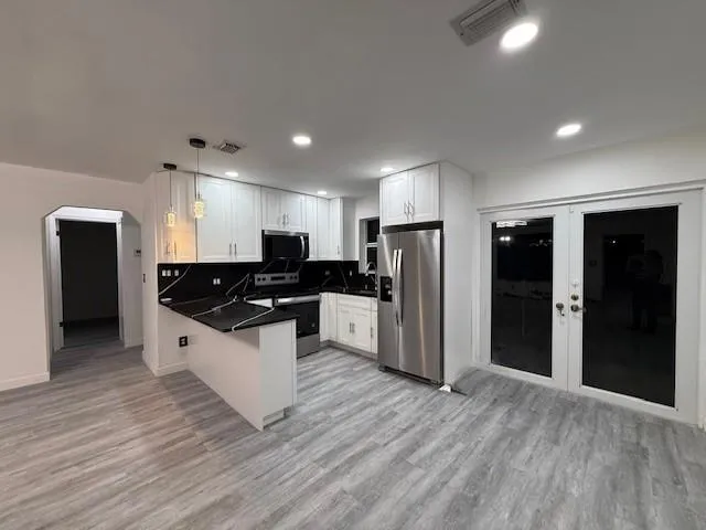 a large white kitchen with stainless steel appliances kitchen island granite countertop a refrigerator and a sink