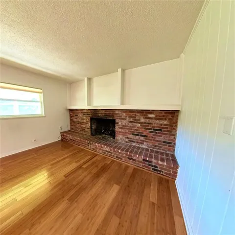 a view of empty room with wooden floor and fireplace