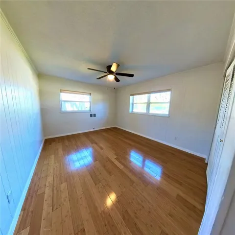 a view of empty room with wooden floor and fan