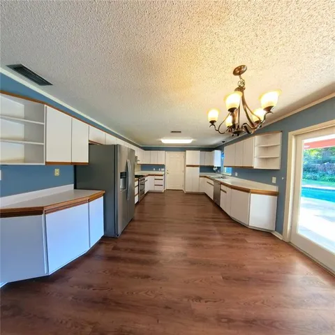 a view of a kitchen with kitchen island a sink wooden floor and stainless steel appliances