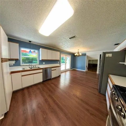 a large kitchen with a large counter top space a stove a wooden floor and a window