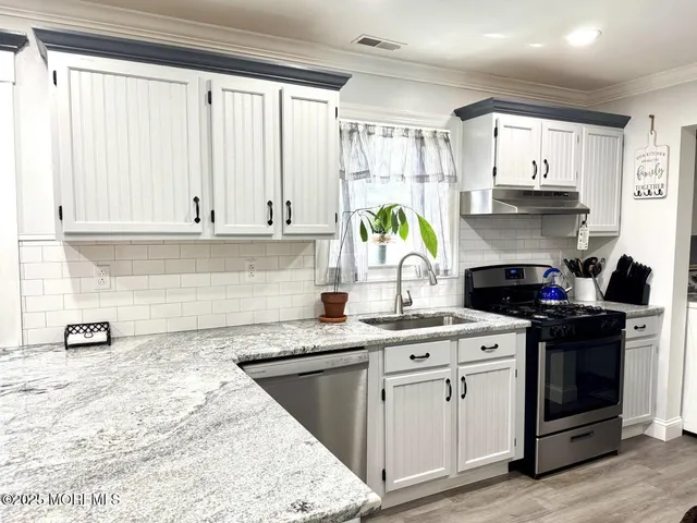 a kitchen with stainless steel appliances granite countertop a sink stove and cabinets