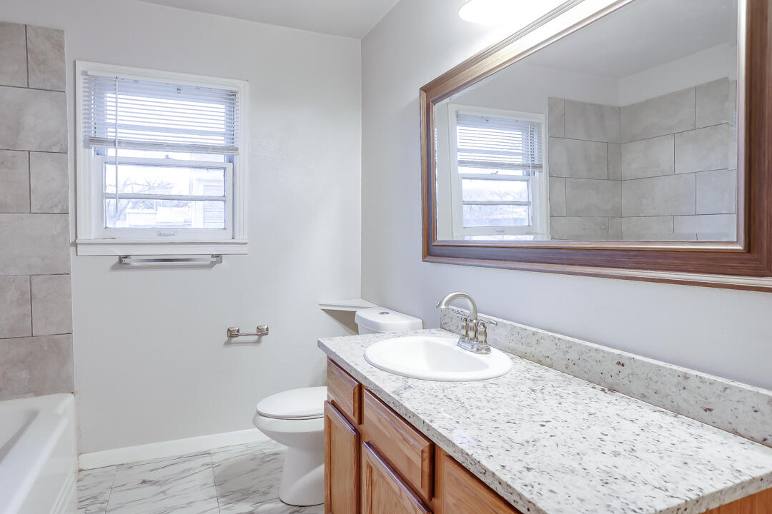3414 24th Street Lubbock, TX 79410 - Photo 10 of 18 a bathroom with a granite countertop sink toilet and mirror