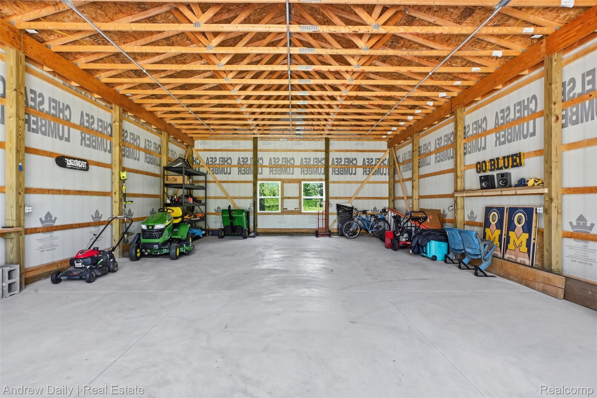 4661 Spears Road Pinckney, MI 48169 - Photo 45 of 56 Spacious outbuilding featuring an exposed wood truss ceiling, concrete slab flooring, two windows, and ample storage capacity