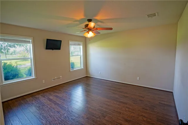 a view of empty room with wooden floor and fan