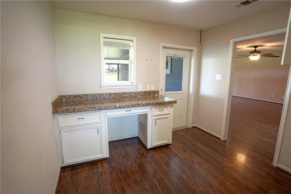 a kitchen with granite countertop white cabinets and wooden floor