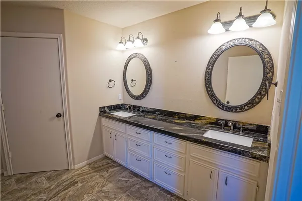 a bathroom with a granite countertop double vanity sink and a mirror