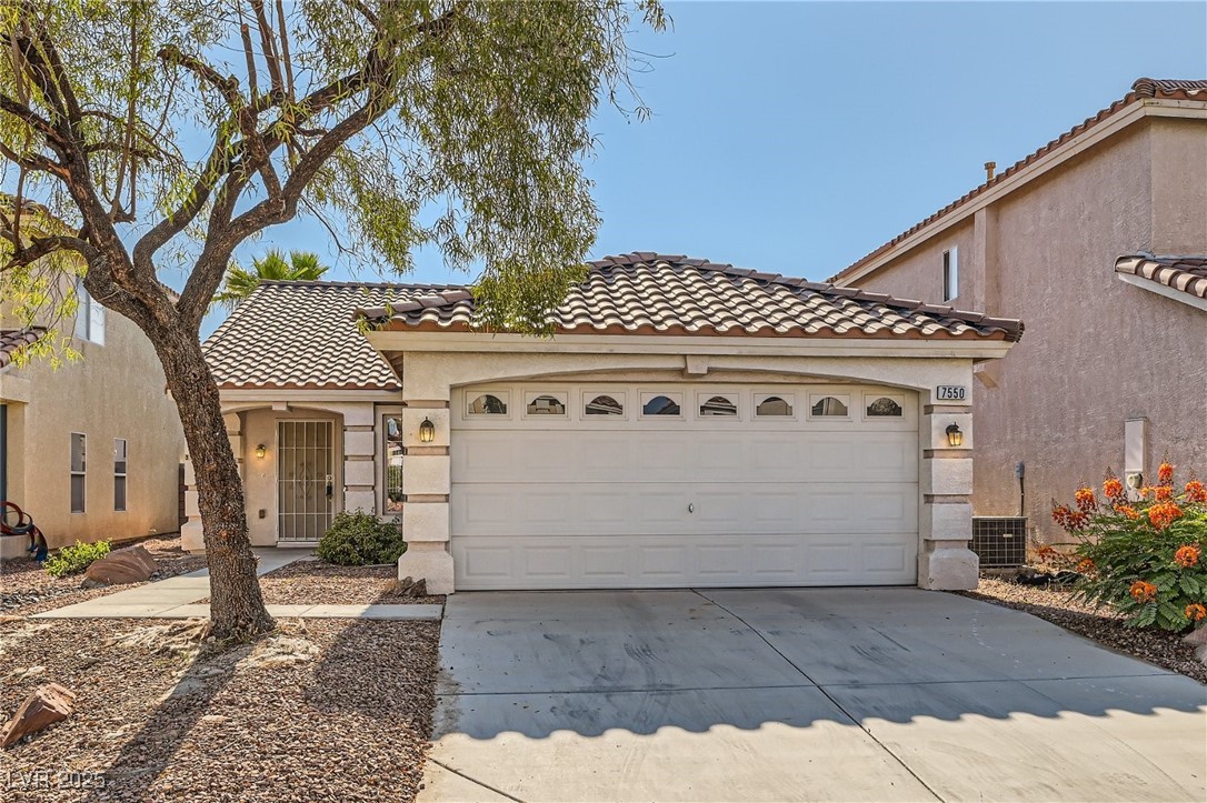Mediterranean / spanish-style house featuring stucco siding, a tiled roof, an attached garage, and concrete driveway