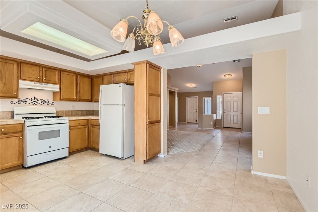 7550 Slipstream Street Las Vegas, NV 89139 - Photo 21 of 33 Kitchen with white appliances, light countertops, decorative light fixtures, a chandelier, and light tile patterned floors