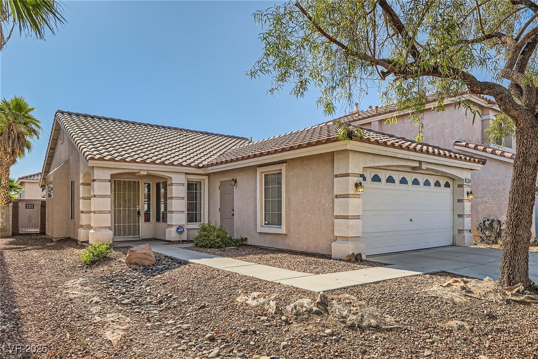 7550 Slipstream Street Las Vegas, NV 89139 - Photo 7 of 33 Mediterranean / spanish house featuring a tile roof, stucco siding, an attached garage, and driveway