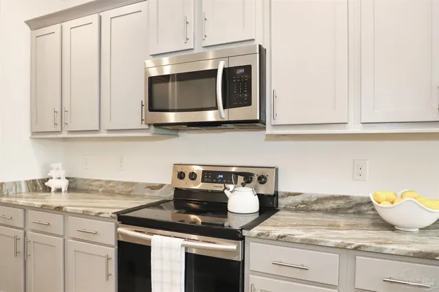 a kitchen with stainless steel appliances granite countertop white cabinets and a stove top oven