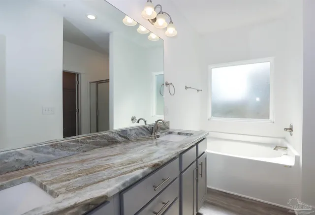 a bathroom with a granite countertop sink a large mirror and a bathtub