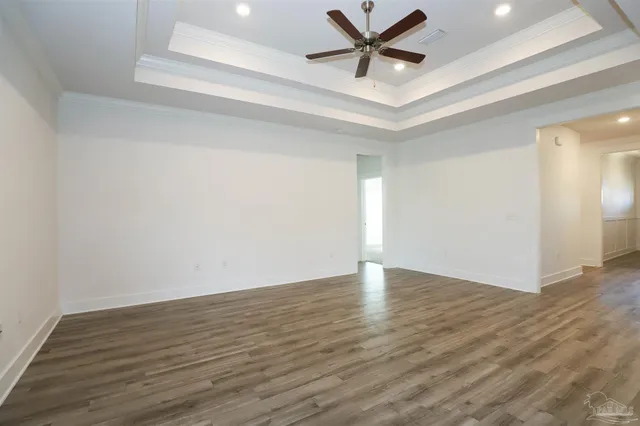 an empty room with wooden floor and a ceiling fan