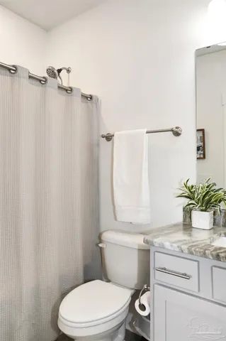 a bathroom with a granite countertop sink toilet and a mirror