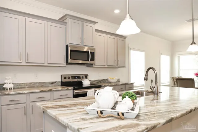 a kitchen with stainless steel appliances granite countertop a stove top oven a sink dishwasher and white cabinets with wooden floor