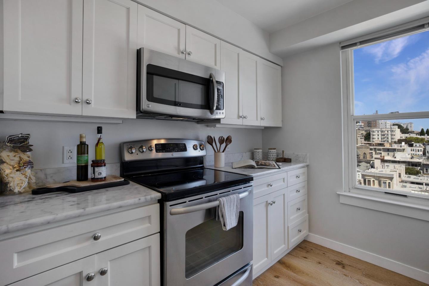 1483 Sutter Street, Unit 1101 San Francisco, CA 94109 - Photo 11 of 39 a kitchen with stainless steel appliances granite countertop white cabinets a stove a microwave and a window