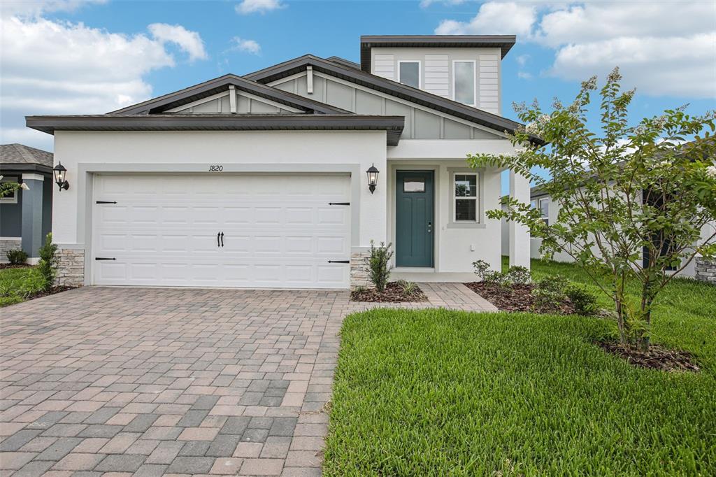 a view of a white house with a small yard and a large tree